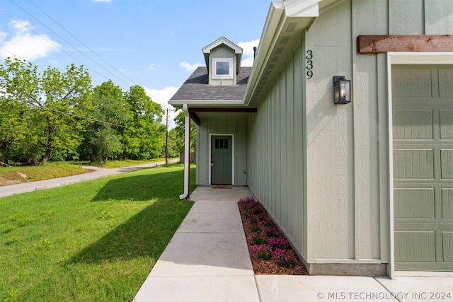 entrance to property featuring a lawn and a garage