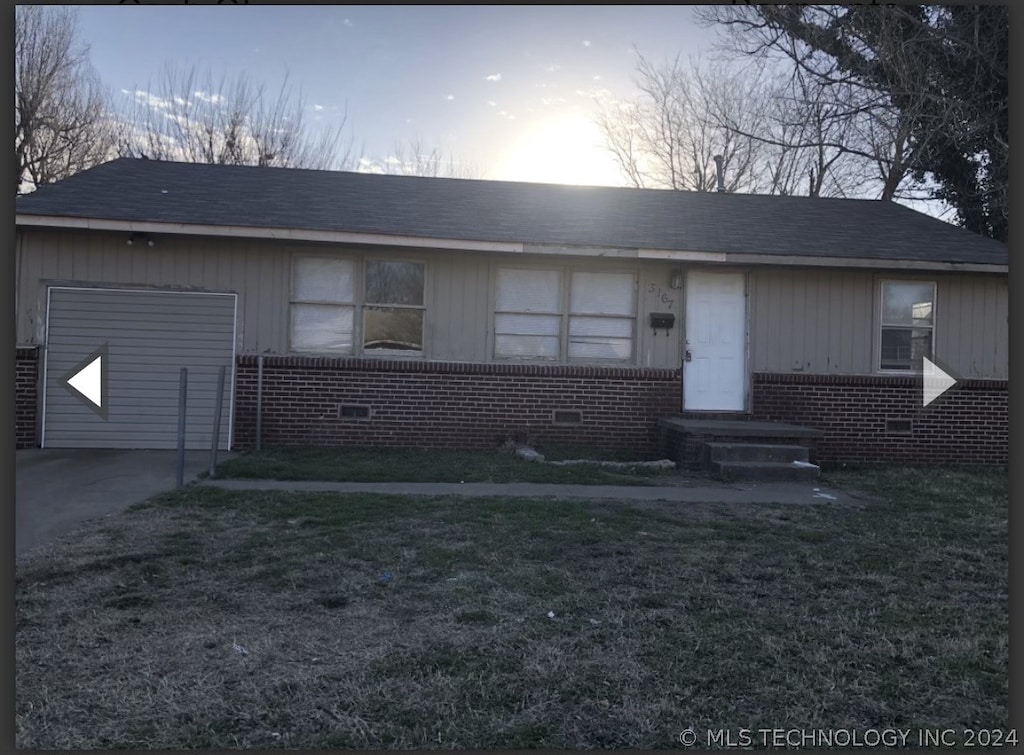 view of front of house with a garage, crawl space, brick siding, and a yard