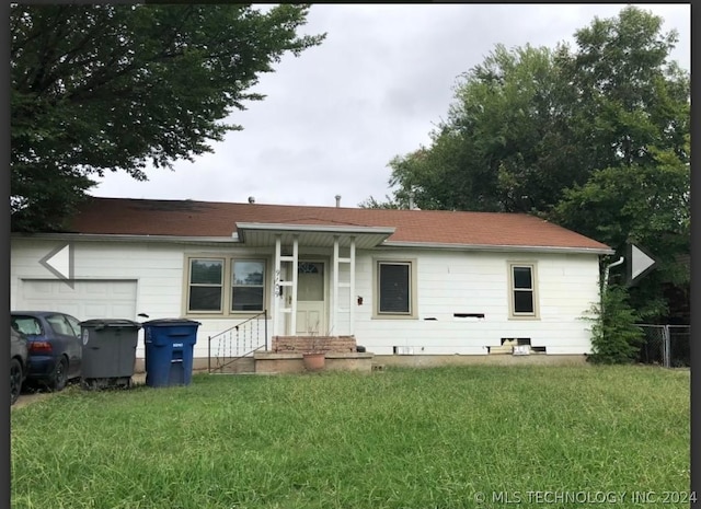 view of front of property featuring a garage, a front yard, and fence