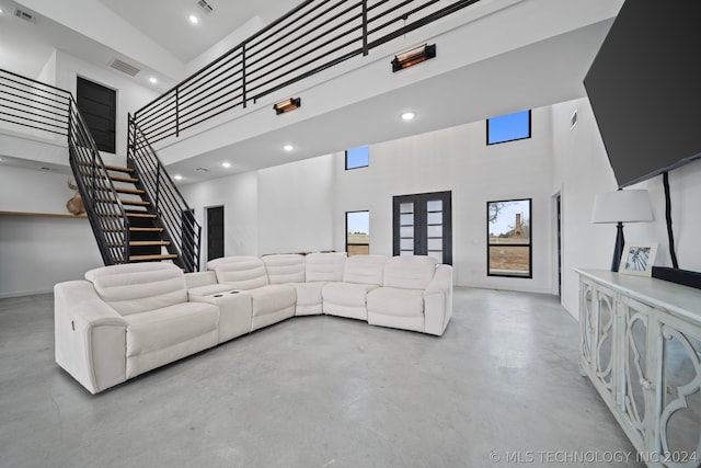 living room featuring concrete flooring, french doors, and a towering ceiling