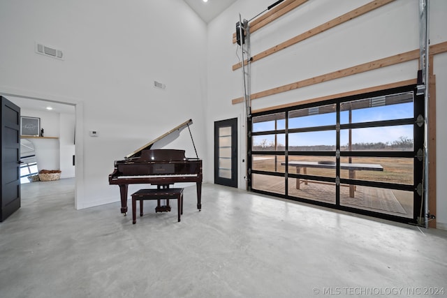 misc room with a towering ceiling and concrete floors