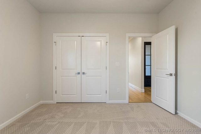 unfurnished bedroom featuring a closet and light colored carpet