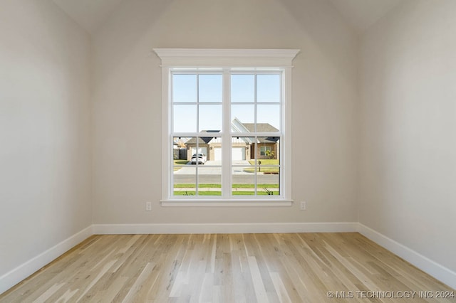 unfurnished room with light wood-type flooring and vaulted ceiling