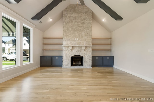 unfurnished living room featuring beamed ceiling, light wood-type flooring, a fireplace, and high vaulted ceiling