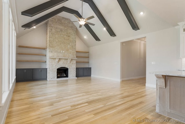 unfurnished living room featuring light hardwood / wood-style floors, beamed ceiling, a fireplace, high vaulted ceiling, and ceiling fan