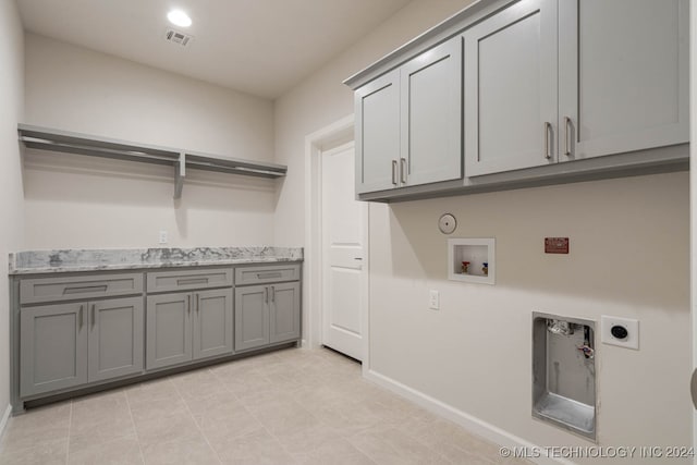 clothes washing area featuring washer hookup, light tile patterned floors, hookup for a gas dryer, electric dryer hookup, and cabinets