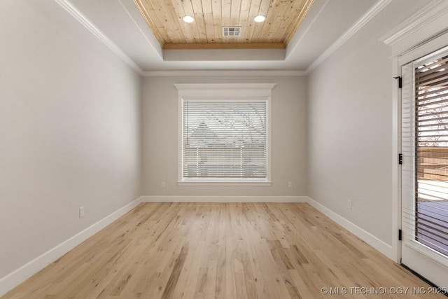 empty room featuring crown molding, a tray ceiling, plenty of natural light, and baseboards