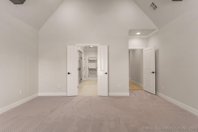 unfurnished bedroom featuring high vaulted ceiling, light carpet, visible vents, baseboards, and a walk in closet