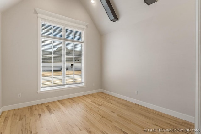 empty room with lofted ceiling, light wood-style flooring, and baseboards