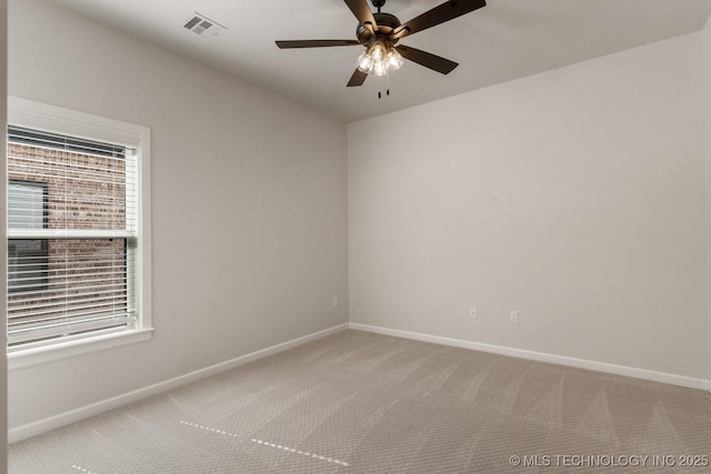 empty room with a wealth of natural light, light carpet, visible vents, and baseboards