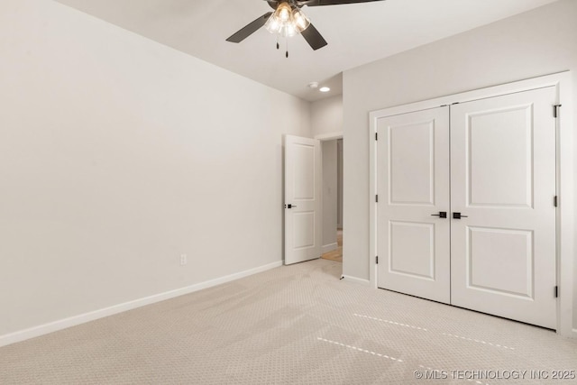 unfurnished bedroom with light carpet, ceiling fan, a closet, and baseboards