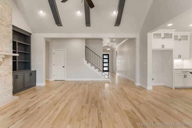 unfurnished living room with vaulted ceiling with beams, ceiling fan, baseboards, stairs, and light wood-style floors