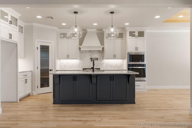 kitchen with white cabinets, glass insert cabinets, stainless steel appliances, light countertops, and premium range hood