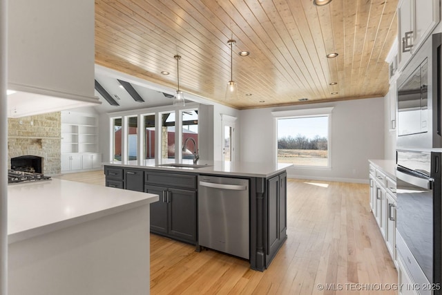 kitchen with stainless steel appliances, a sink, built in features, open floor plan, and a center island with sink