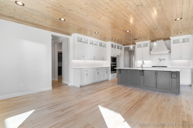 kitchen with appliances with stainless steel finishes, light countertops, custom exhaust hood, and tasteful backsplash