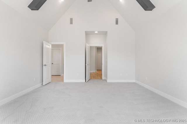 unfurnished bedroom featuring light carpet, high vaulted ceiling, visible vents, and baseboards