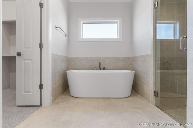 bathroom featuring a wealth of natural light, a stall shower, tile patterned flooring, and a freestanding bath