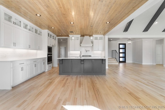 kitchen with recessed lighting, light countertops, custom range hood, wall oven, and white cabinetry