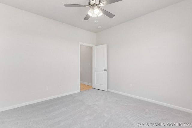 carpeted spare room with baseboards and a ceiling fan