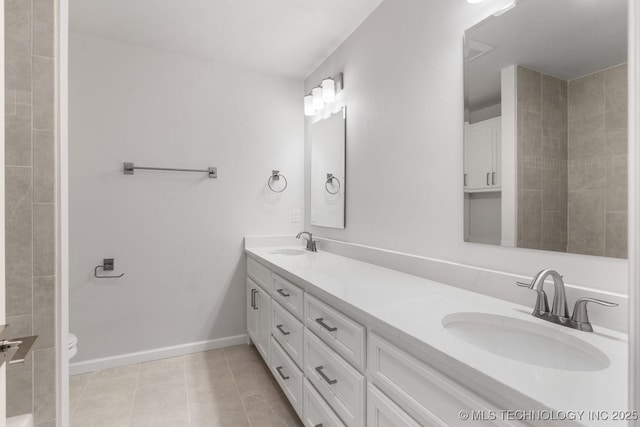 full bathroom with double vanity, tile patterned flooring, baseboards, and a sink