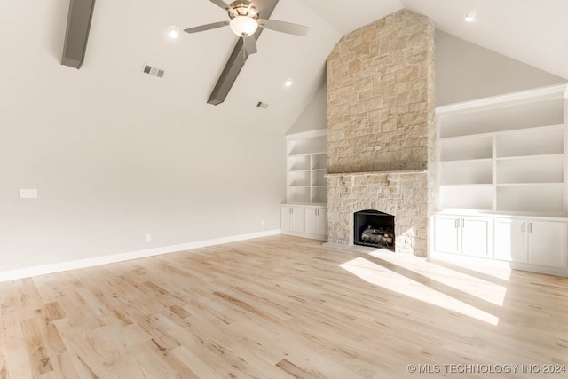 unfurnished living room featuring light hardwood / wood-style floors, high vaulted ceiling, beam ceiling, a fireplace, and built in features