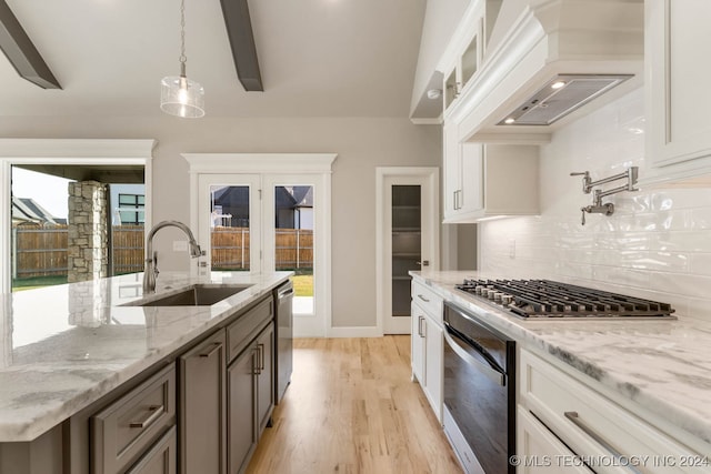 kitchen with white cabinetry, sink, tasteful backsplash, custom exhaust hood, and decorative light fixtures