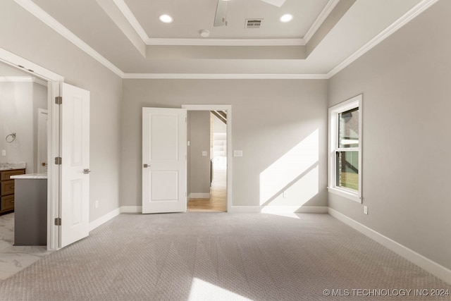 unfurnished bedroom with ornamental molding, light carpet, ceiling fan, and a tray ceiling