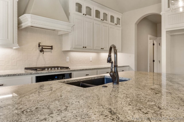 kitchen with sink, stainless steel gas cooktop, tasteful backsplash, white cabinets, and custom exhaust hood