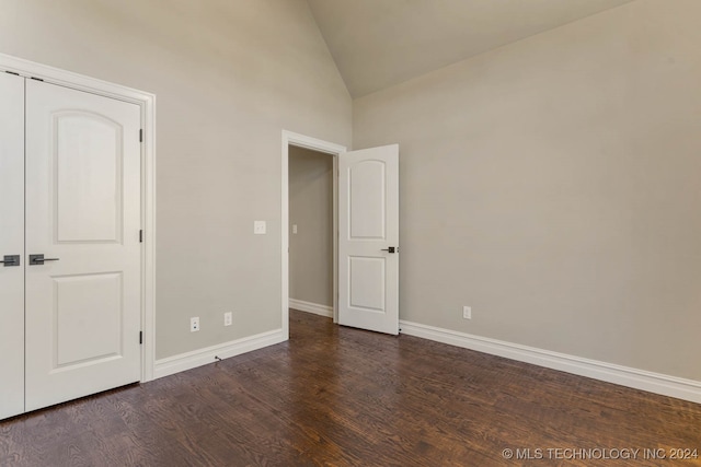 unfurnished bedroom with a closet, dark hardwood / wood-style flooring, and high vaulted ceiling