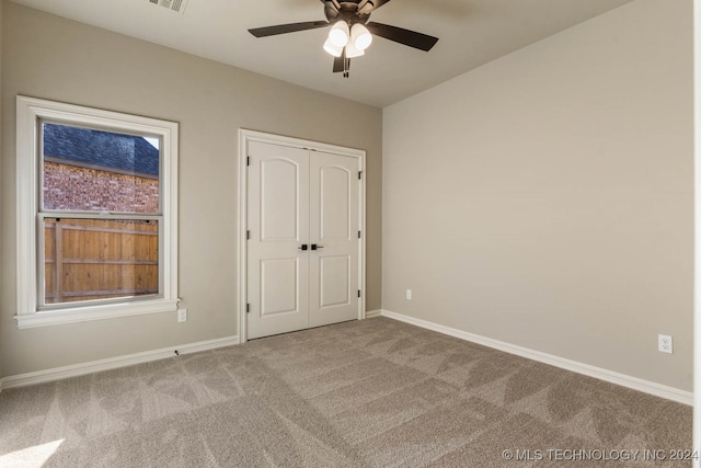 unfurnished bedroom featuring light carpet, a closet, and ceiling fan