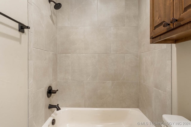 bathroom featuring tiled shower / bath combo and toilet