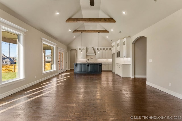 unfurnished living room featuring beam ceiling, sink, dark wood-type flooring, and high vaulted ceiling