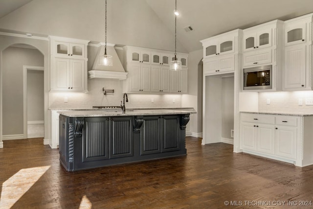 kitchen featuring stainless steel microwave, high vaulted ceiling, white cabinets, tasteful backsplash, and light stone counters