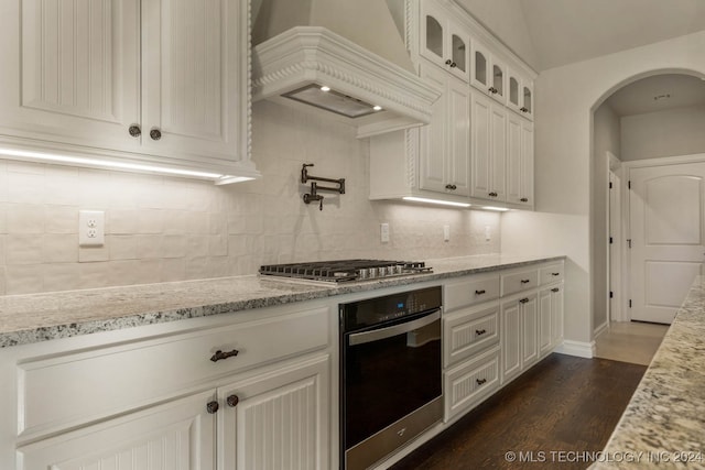 kitchen with appliances with stainless steel finishes, tasteful backsplash, custom range hood, white cabinets, and dark hardwood / wood-style floors