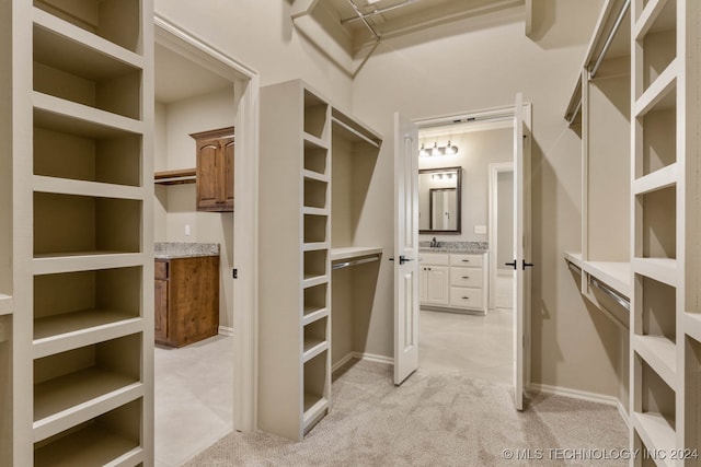 walk in closet featuring sink and light colored carpet