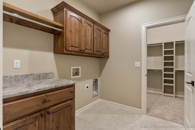 clothes washing area featuring hookup for an electric dryer, cabinets, light tile patterned floors, and washer hookup