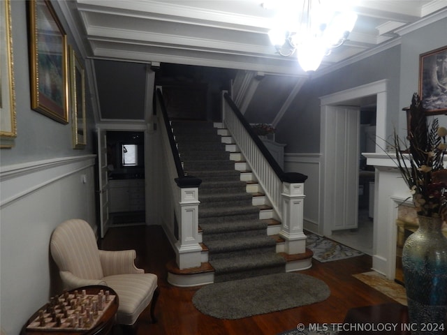 stairs featuring ornamental molding, wood-type flooring, and a chandelier