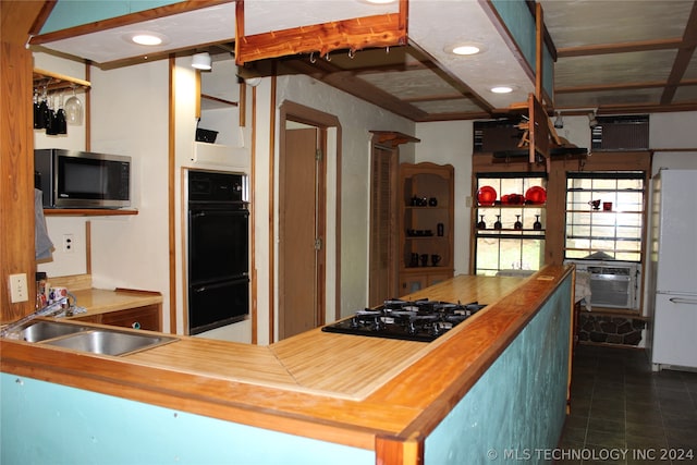 kitchen featuring wood counters, dark tile floors, black appliances, and sink