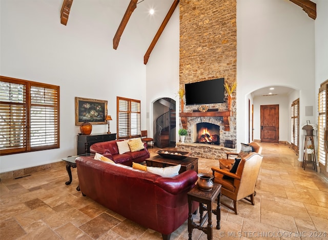 living room featuring beam ceiling, plenty of natural light, a fireplace, and high vaulted ceiling