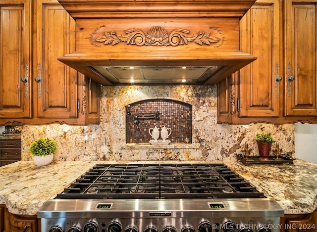 room details with premium range hood, light stone countertops, stainless steel range, and backsplash