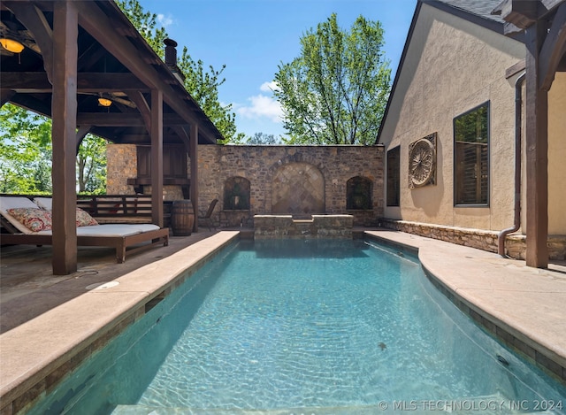 view of pool with a patio and an outdoor stone fireplace