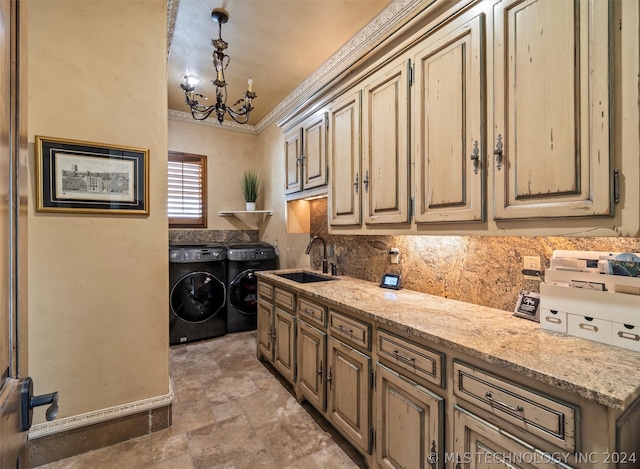 washroom with sink, crown molding, cabinets, washer and dryer, and a notable chandelier