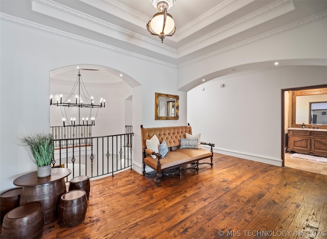 living area featuring ornamental molding, a tray ceiling, a chandelier, and wood-type flooring