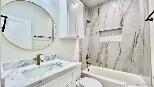 full bathroom featuring tiled shower / bath, vanity, and toilet