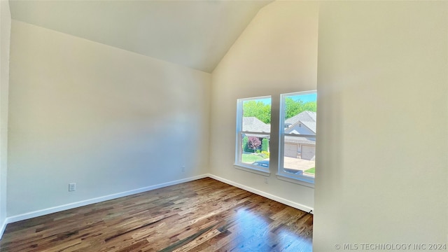 spare room featuring high vaulted ceiling and dark hardwood / wood-style floors