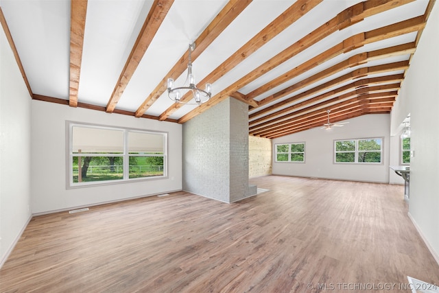 interior space with lofted ceiling with beams, ceiling fan with notable chandelier, hardwood / wood-style floors, and brick wall