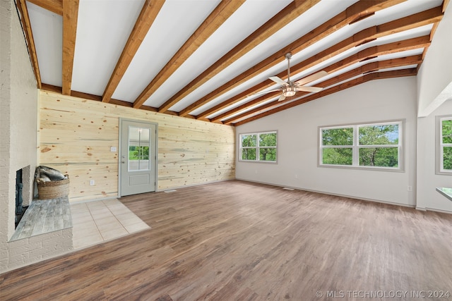 unfurnished living room featuring wood walls, hardwood / wood-style floors, lofted ceiling with beams, and a fireplace