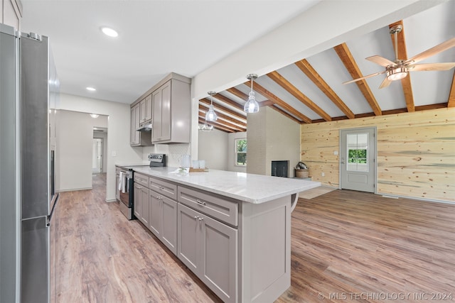 kitchen featuring wood walls, lofted ceiling with beams, stainless steel appliances, and light wood-type flooring