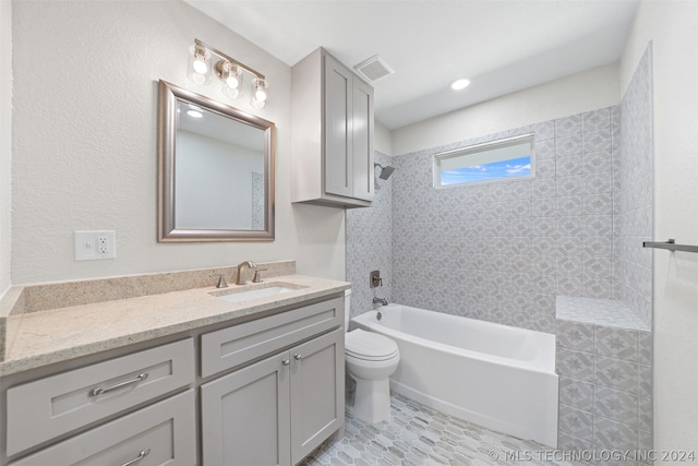 full bathroom featuring tile floors, tiled shower / bath, vanity, and toilet