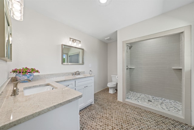 bathroom featuring tiled shower, tile flooring, toilet, and large vanity